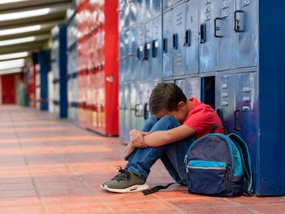 Niño que sufre acoso escolar sentado en el suelo, en una foto de archivo.