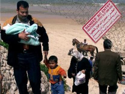 Un palestino con sus dos hijos esquiva el bloqueo israelí de las carreteras de Gaza dando un rodeo por la playa.