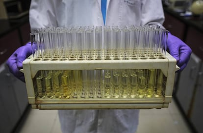 Un empleado de una compañía farmacéutica porta varios tubos de ensayo.