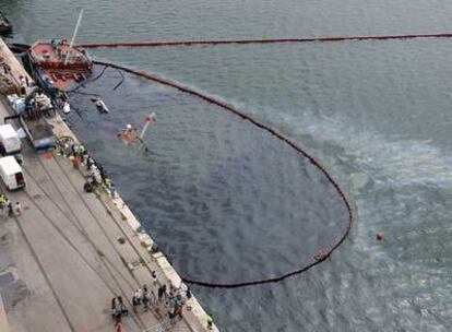 La gabarra semihundida, con las barreras flotantes para contener el vertido.