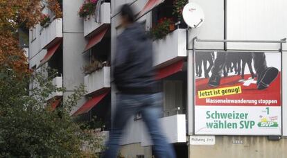 Un transeúnte pasa ante un cartel del derechista SVP/UDC que llama a “frenar la inmigración masiva”
