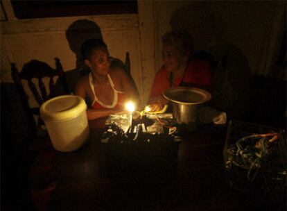 Dos mujeres charlan en la oscuridad en una vivienda de La Habana afectada por un corte de suministro de energía eléctrica.