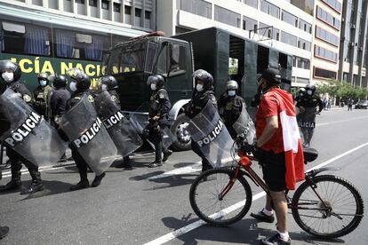 Un ciclista pasa delante de un grupo de Policías en Lima tras la renuncia de Manuel Merino a la Presidencia de Perú.