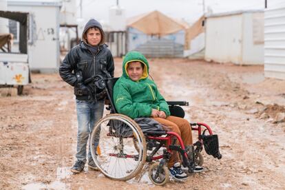 El 17 de febrero de 2017 en Jordania, Hikmat (derecha), de 12 años, es empujado por el campamento de refugiados de Zaatari por su amigo Abdullah, de 11. Aunque parte del campamento es accesible para sillas de ruedas, la grava y el barro hacen que sea imposible para Hikmat empujarse. Los niños vivían en Jordania desde que huyeron de Siria hacía cinco años. El campamento de Zaatari en Jordania albergaba a unos 80.000 refugiados sirios. Entre ellos, Hikmat y Abdullah, que desde que se conocieron en 2016 se hicieron amigos inseparables.