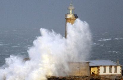Una ola sobre el faro de la isla de Mouro, en Santander.