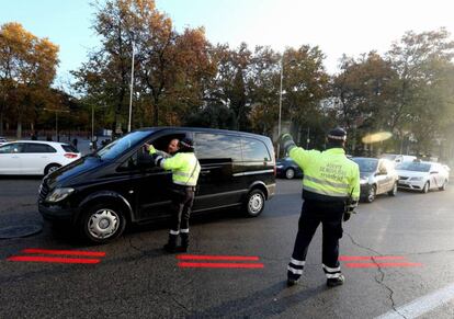 Dos agentes de Movilidad informan a un conductor sobre Madrid Central; en el suelo, la línea roja que delimita el área.
