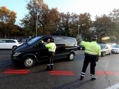Dos agentes de Movilidad informan a un conductor sobre Madrid Central; en el suelo, la línea roja que delimita el área. 