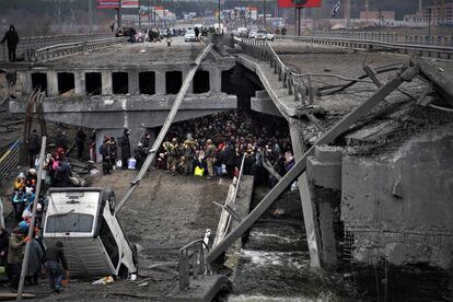 Un grupo de ucranios intenta pasar por debajo de un puente destruido por un bombardeo ruso en Irpín, cerca de Kiev, el 5 de marzo. 