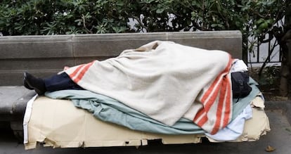 Un sense sostre dormint a un banc de Barcelona.