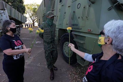 Duas militantes que fizeram oposição à ditadura brasileira oferecem flores a militar, em Brasília.