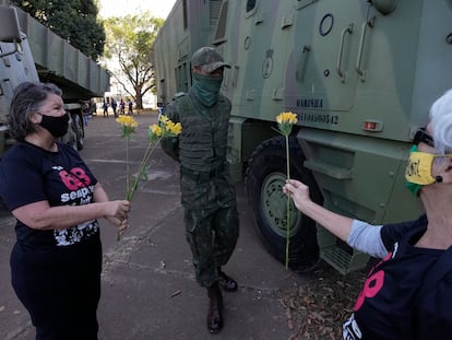 Duas militantes que fizeram oposição à ditadura brasileira oferecem flores a militar, em Brasília.