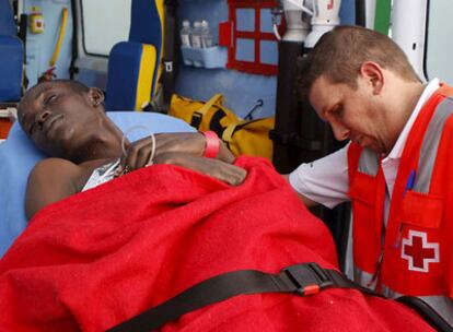 Un miembro de la Cruz Roja atiende a uno de los 76 inmigrantes que viajaban a bordo del cayuco llegado hoy a Tenerife.