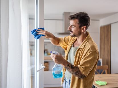 Un chico limpiando las ventanas de sus casa.