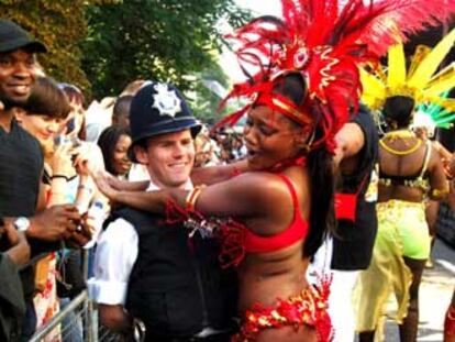 Una participante en el carnaval de Notting Hill baila con un policía.