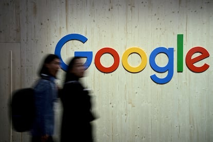 Dos personas caminan frente a un logo de Google, en Hanover (Alemania) en 2024.