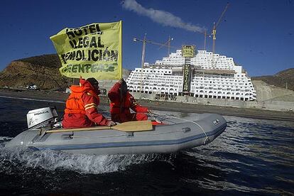 Dos miembros de la organización ecologista frente al hotel del que piden la demolición