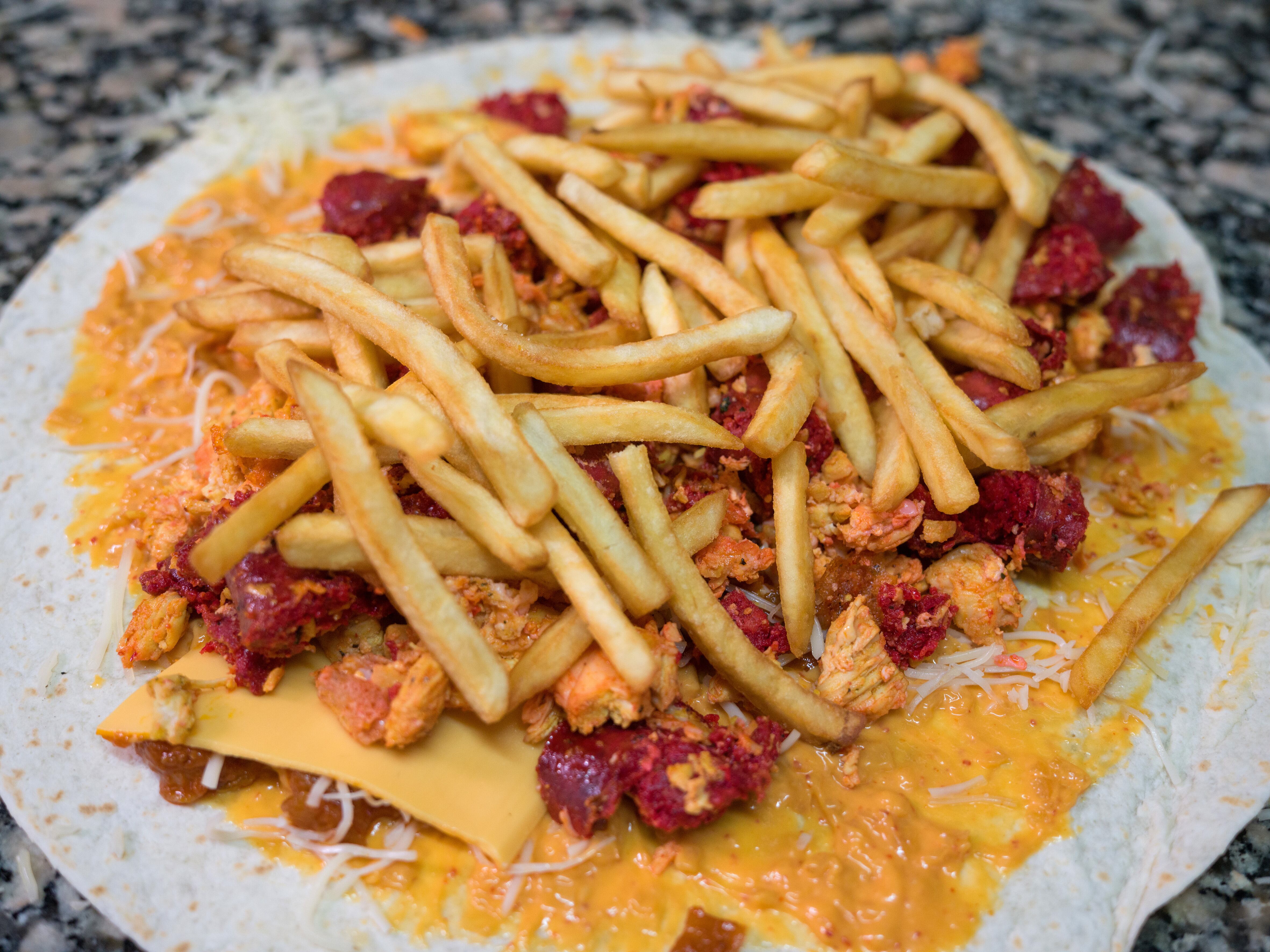 Taco de merguez, pollo, patatas fritas y queso preparado para ir al horno en el local Mister Tacos.