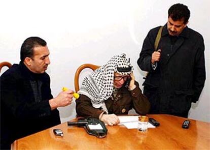 Arafat, entre sus guardaespaldas, habla por teléfono esta mañana desde su cuartel general en Ramala.