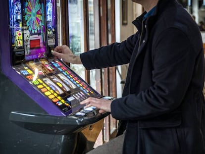 Un hombre echa una moneda a una máquina tragaperras en un bar de Valencia.