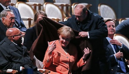 El presidente de Rusia Vladimir Putin cubre con un abrigo a la canciller alemana Angela Merkel durante la presentación de una fuente musical, 5 de septiembre de 2013, durante la Cumbre del G-20 en San Petersburgo (Rusia).