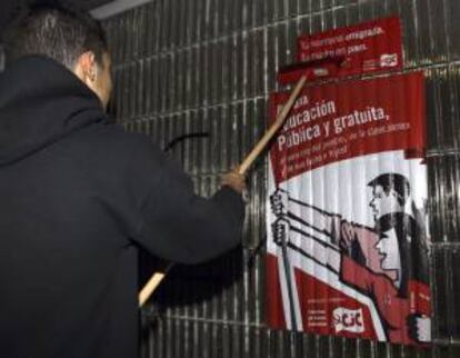 Un joven coloca un cartel informativo de la huelga general de toda la enseñanza pública y privada concertada, que  comienza hoy con el paro de tres jornadas convocado en las enseñanzas medias por el Sindicato de Estudiantes (SE) en protesta por la LOMCE.