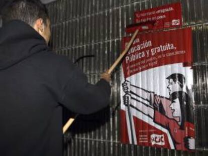 Un joven coloca un cartel informativo de la huelga general de toda la enseñanza pública y privada concertada, que comienza hoy con el paro de tres jornadas convocado en las enseñanzas medias por el Sindicato de Estudiantes (SE) en protesta por la LOMCE.