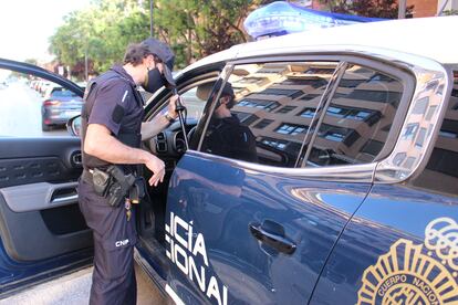 Un agente de la Policía Nacional junto a un coche patrulla.