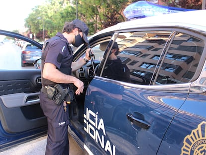 Un agente de la Policía Nacional junto a un coche patrulla.