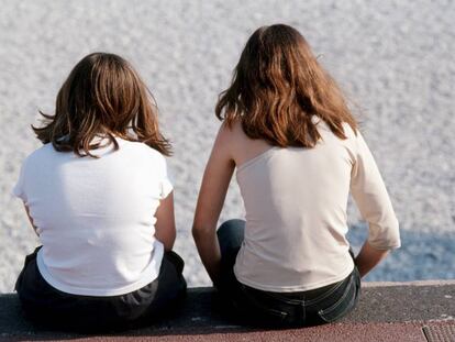 Dos chicas, sentadas en un paseo mar&iacute;timo.