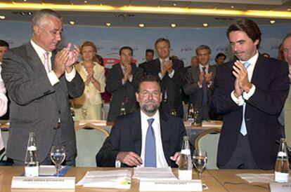 Javier Arenas y José María Aznar aplauden la elección de Mariano Rajoy como líder del PP en la reunión de ayer de la Junta Directiva del partido.