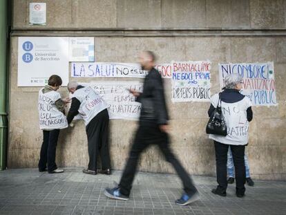 Miembros de Tancada Cl&iacute;nic pegan carteles contra la privatizaci&oacute;n en la fachada del centro p&uacute;blico.
