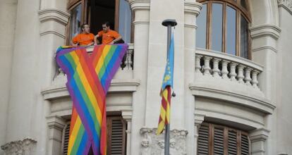 Miembros de Gay Valencia colocan el lazo en el Ayuntamiento.