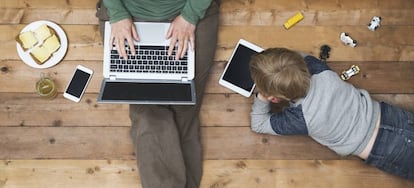 En la imagen una madre con su hijo utilizando dispositivos digitales