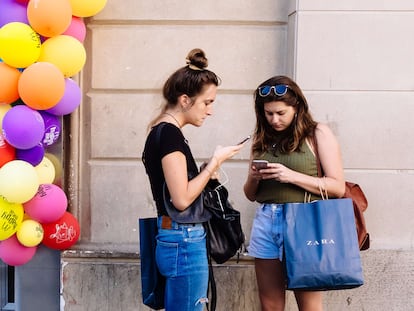 Dos jóvenes con sus teléfonos móviles en Barcelona.