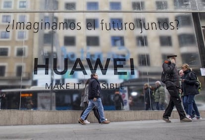 Varias personas pasean por la Gran Vía de Madrid, junto a la futura tienda de Huawei.