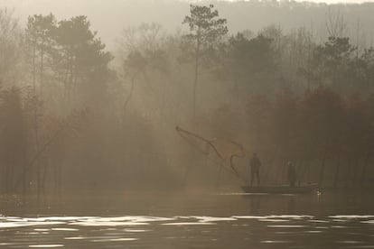 Dos pescadores lanzan una red de pesca en un lago de Huai'an (China).