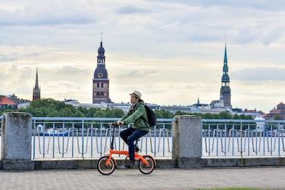 Un ciclista junto al río Daugava, con vistas de la ciudad de Riga.