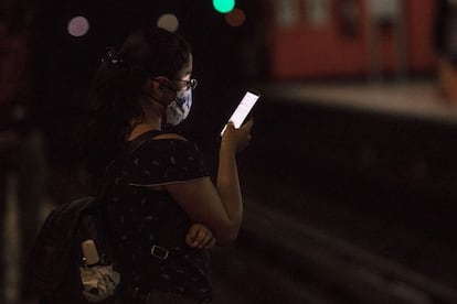 Una mujer usa su celular mientras espera la llegada del Metro.