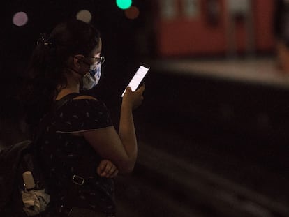 Una mujer usa su celular mientras espera la llegada del Metro.