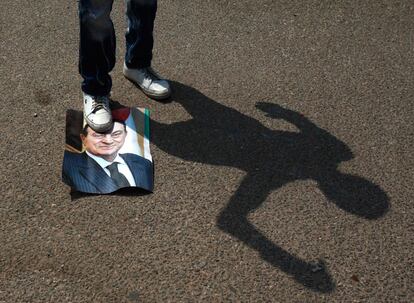 Un opositor al exdictador egipcio Hosni Mubarak pisa una fotografía del 'rais' frente a la academia de policía de El Cairo, donde es juzgado.