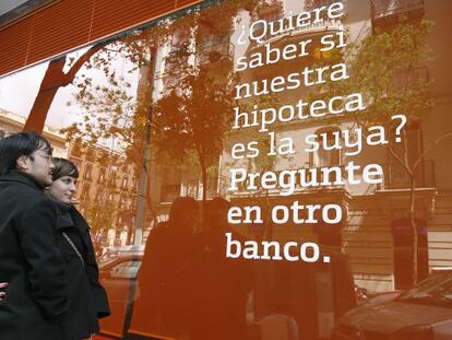 Una pareja lee un anuncio de una hipoteca en una ofician bancaria.