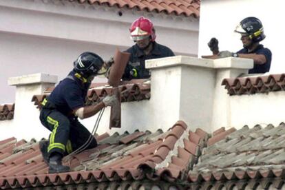 Tres bomberos retiran tejas arrancadas por la tormenta tropical Delta de un tejado de Tenerife.