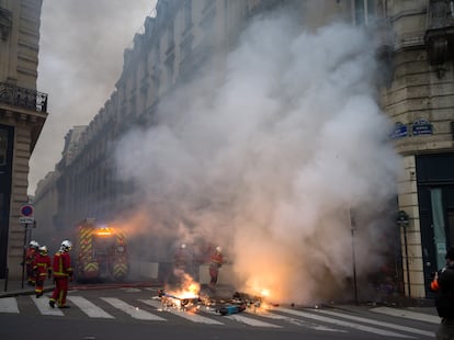Unos bomberos apagan un fuego originado por la quema de basura en una calle de París, el jueves.