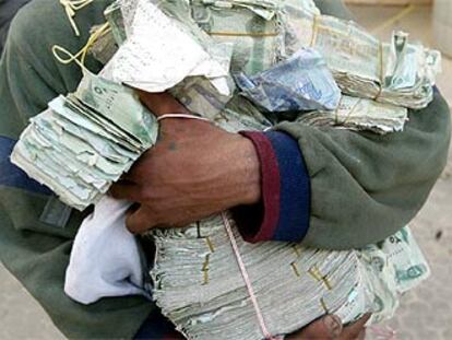 Un iraquí muestra los fajos de billetes que ha robado de un banco asaltado en Bagdad, el jueves.