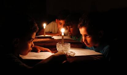 Ni&ntilde;os palestinos estudian en Gaza a la luz de las velas a causa de los apagones.