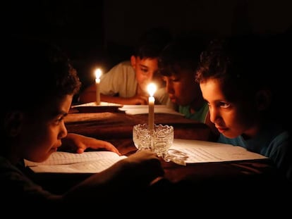 Ni&ntilde;os palestinos estudian en Gaza a la luz de las velas a causa de los apagones.