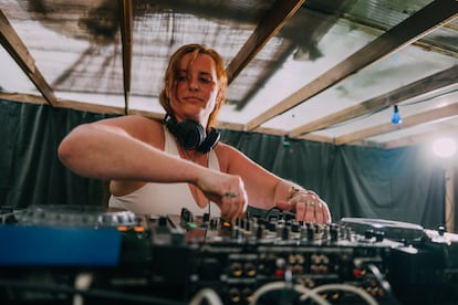 Una DJ mezcla música en un evento al aire libre.