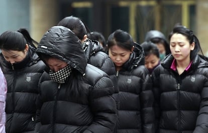 Un grupo de mujeres norcoreanas en las calles de Dandong, China, en marzo de 2023, supervisadas por un vigilante del Gobierno. 
