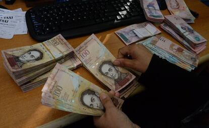Una mujer cuenta billetes de 100 bolívares en Caracas.
