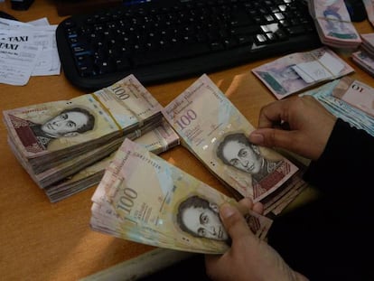 Una mujer cuenta billetes de 100 bolívares en Caracas.